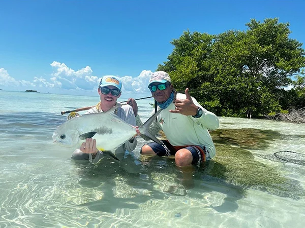 Two people holding a fish in the water.