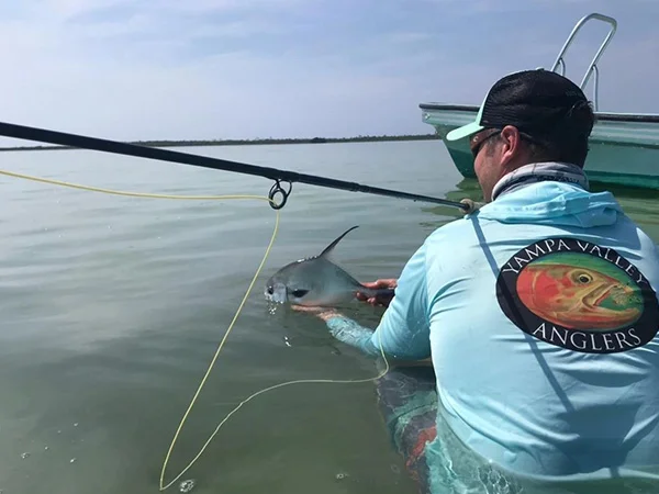 A man holding onto a fish while standing in the water.