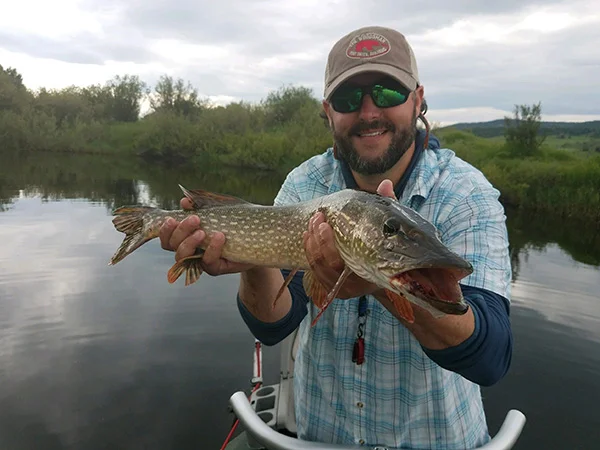 A man holding a fish while standing on top of a boat.