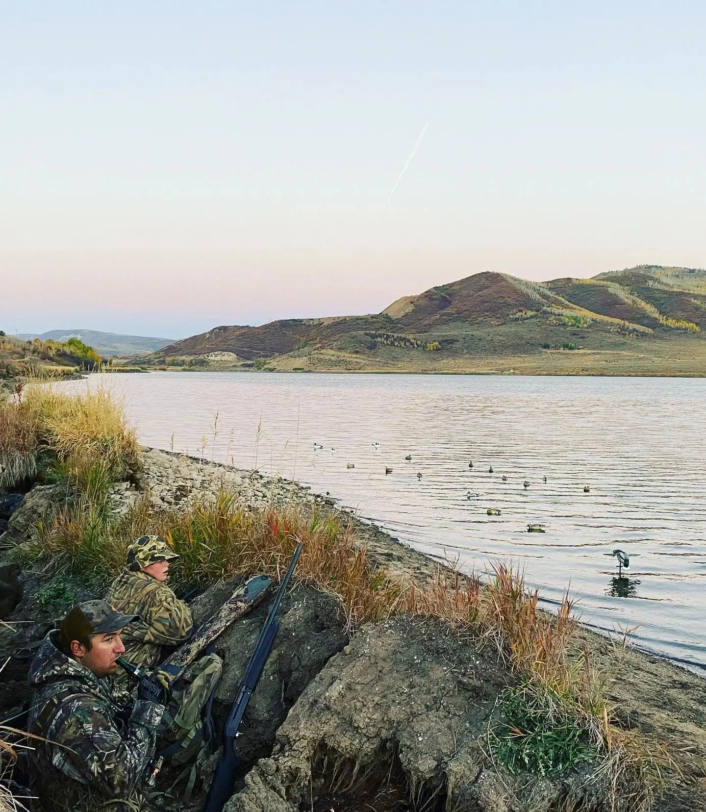 A lake with ducks swimming in it and people on the shore.