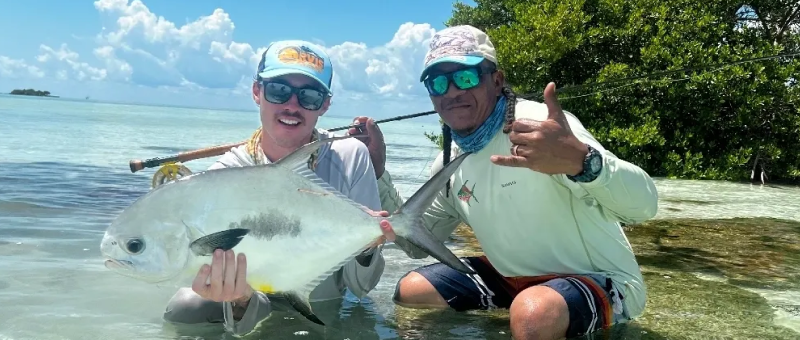 Two people holding up a fish in the water.