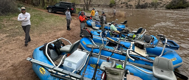 A group of people standing next to blue boats.