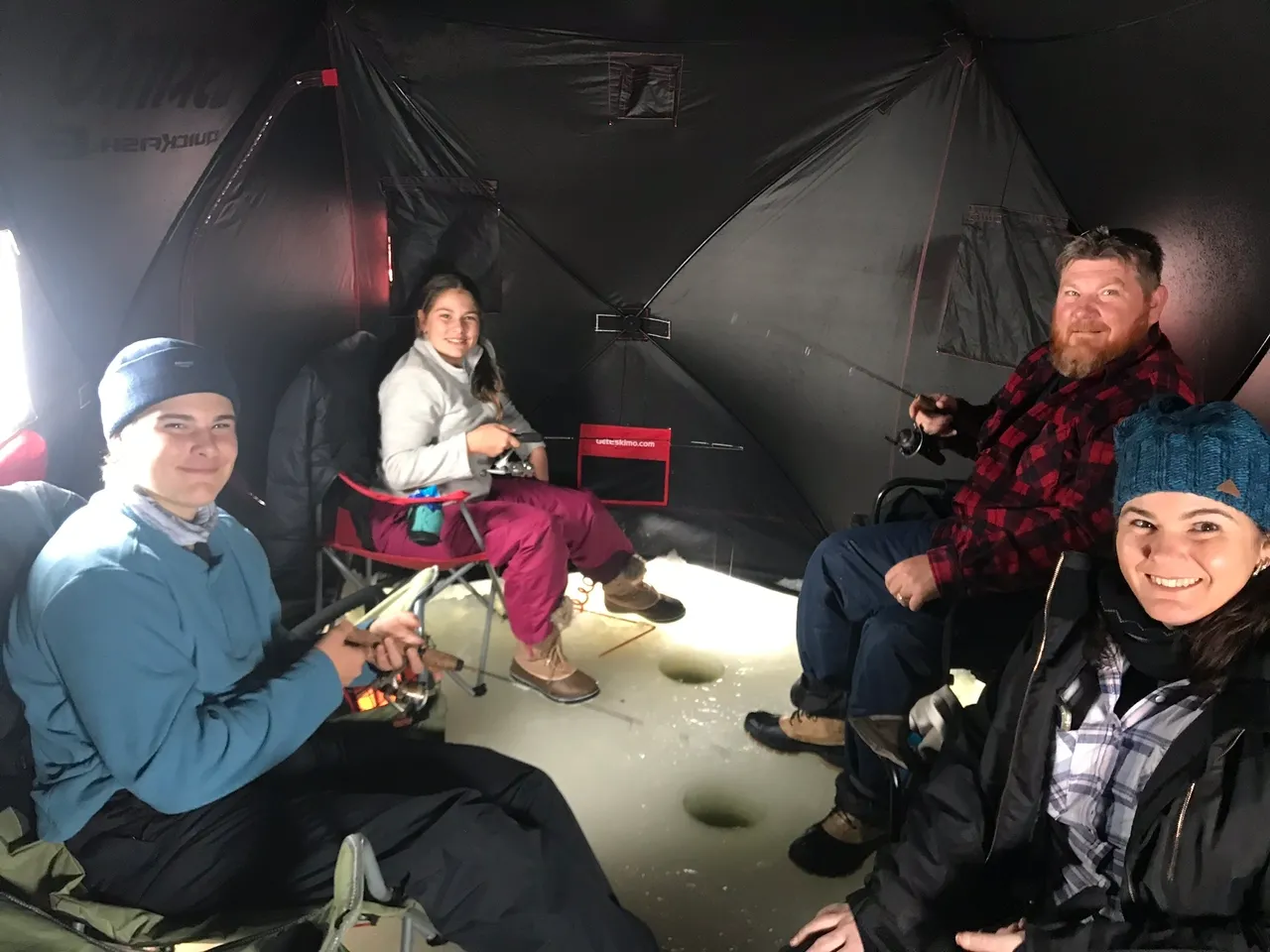 A group of people sitting under an umbrella.