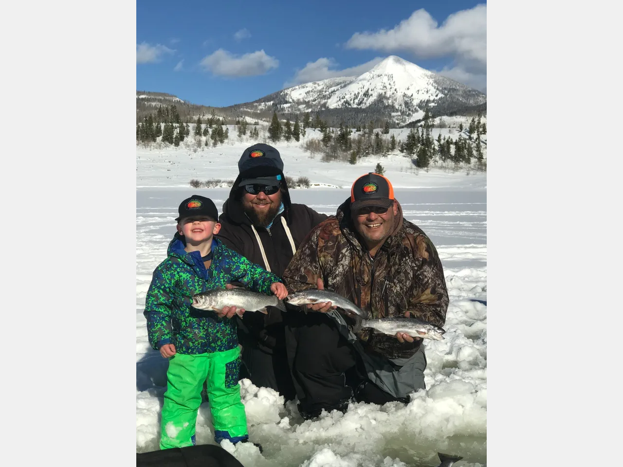 A family holding two fish in the snow.