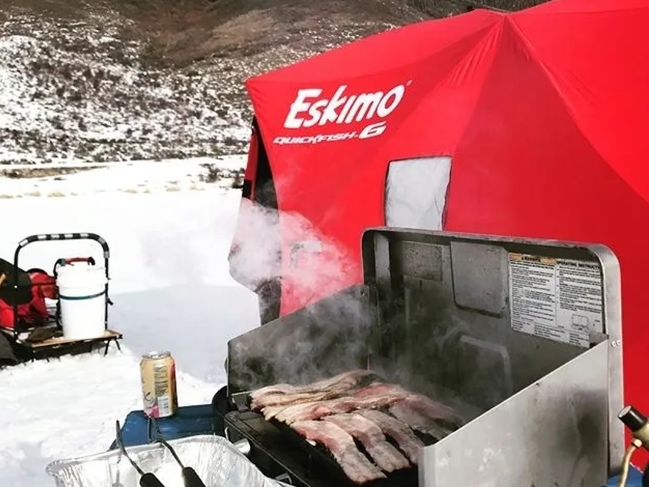 A red bbq with meat cooking on it.