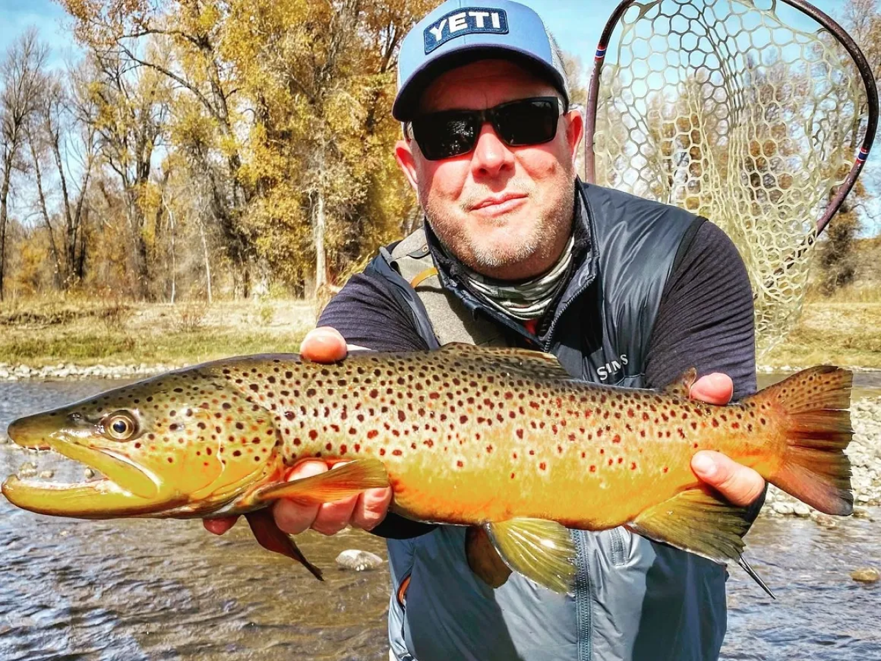 A man holding a brown fish in his hands.