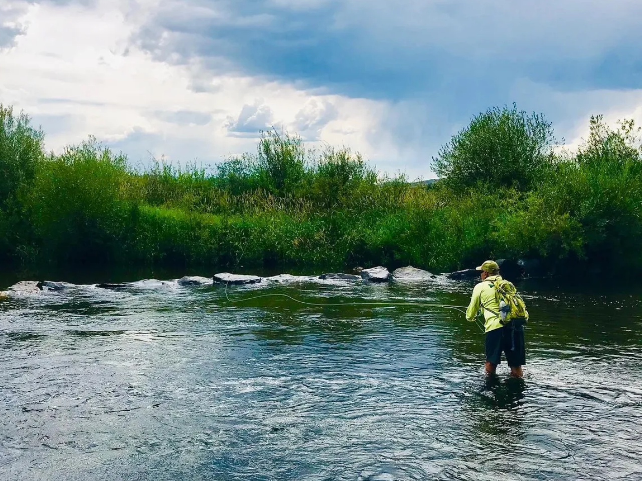 A man standing in the water with a fishing rod.