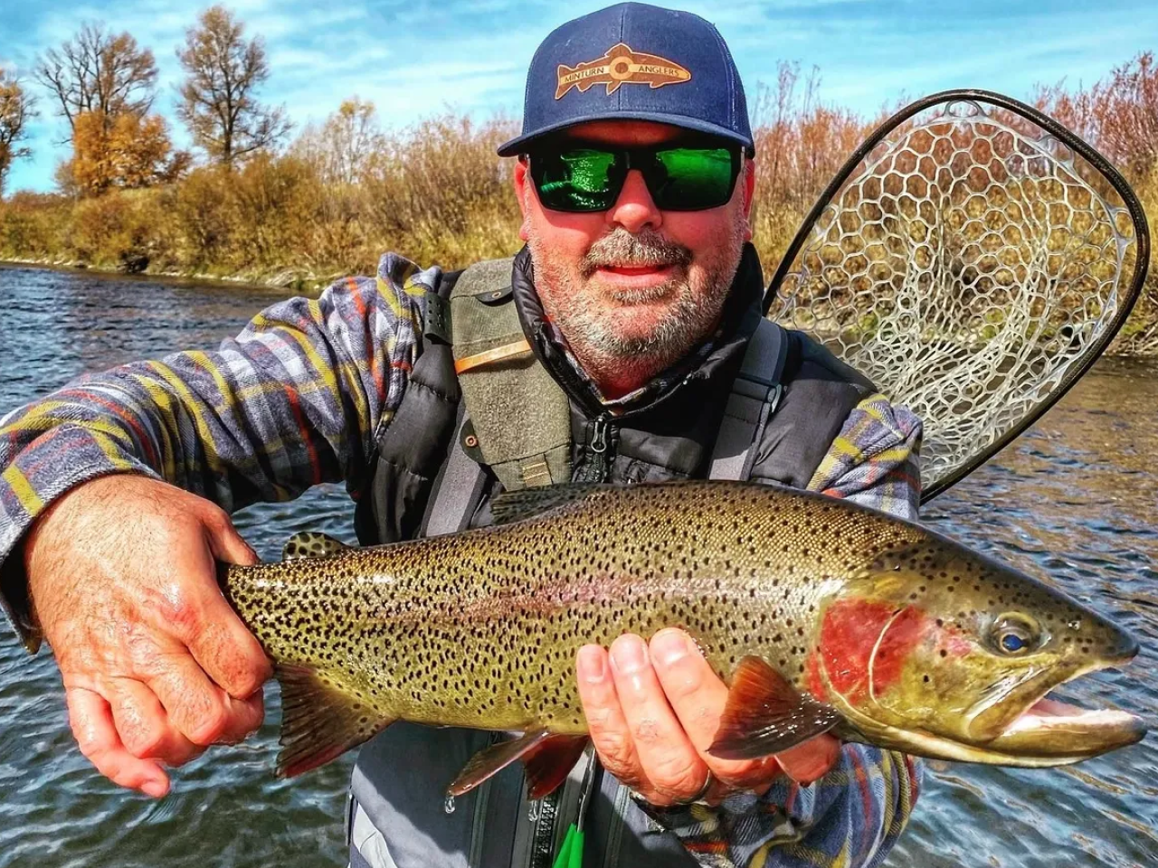 A man holding a fish while wearing sunglasses.