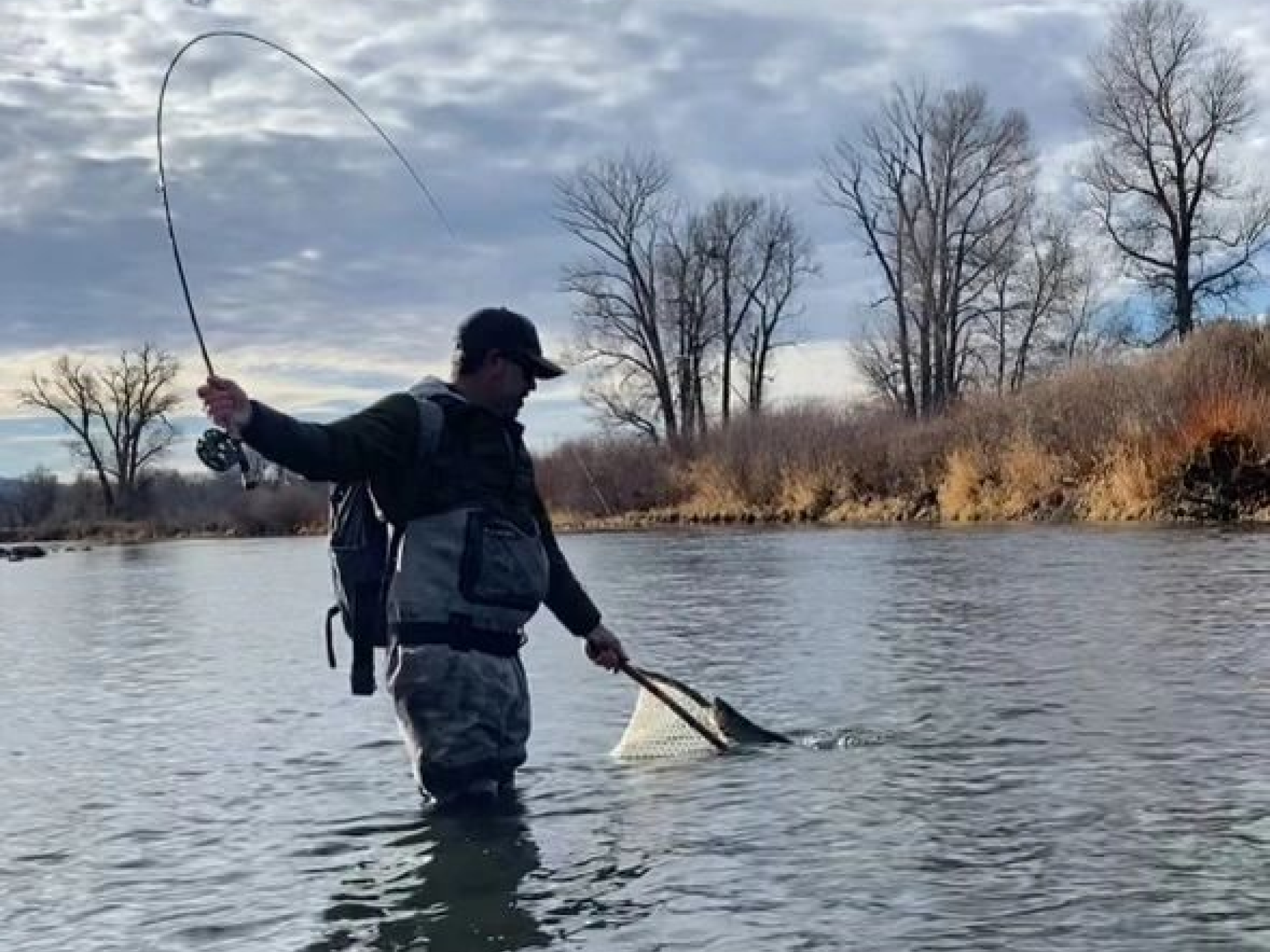 A man in the water holding a fishing rod.