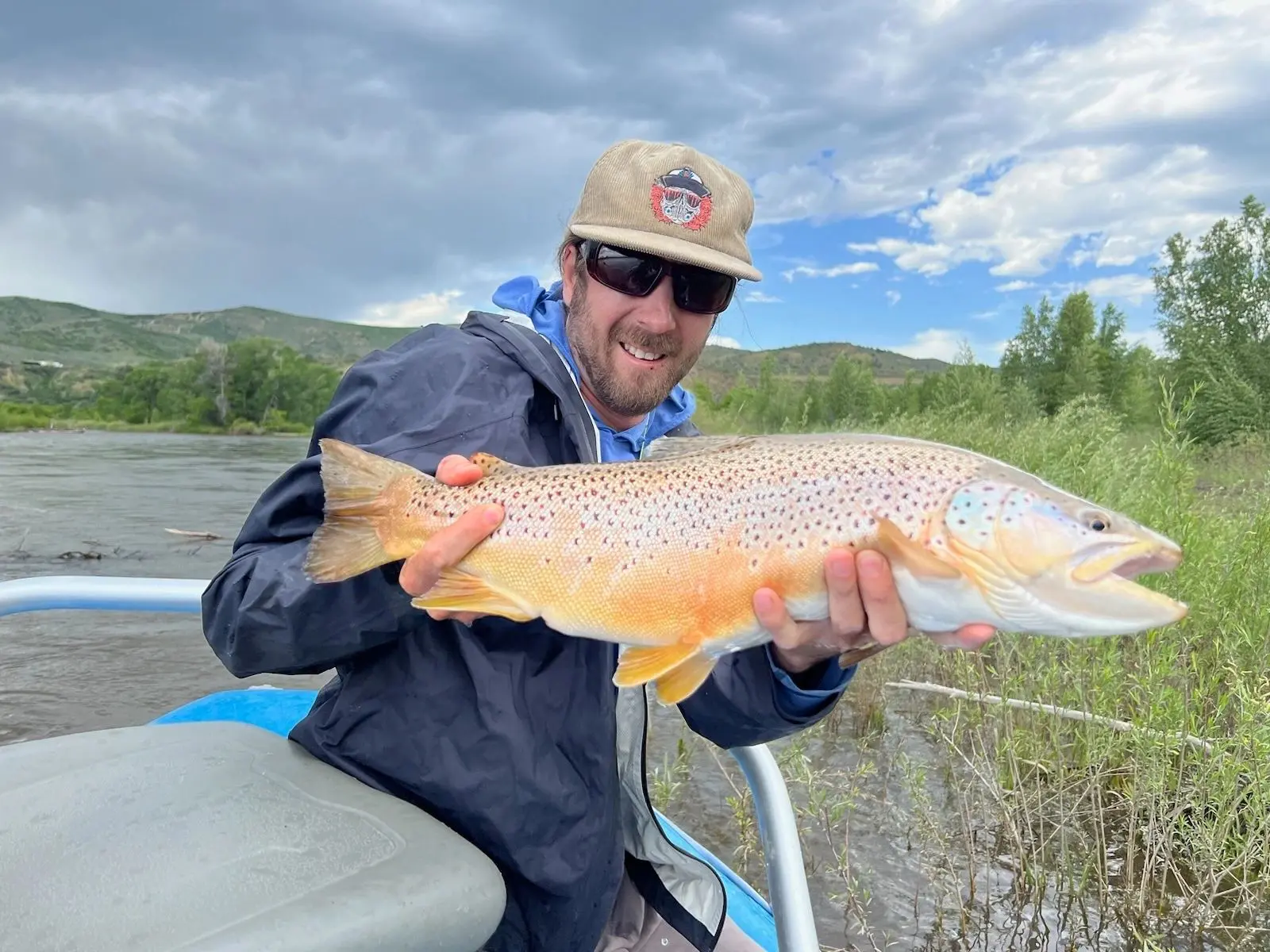 A man holding a fish while sitting on top of a boat.