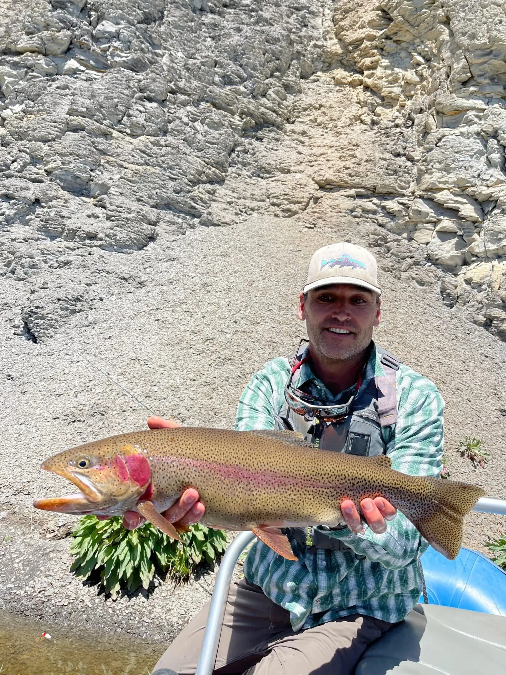 A man holding a fish while standing on top of rocks.