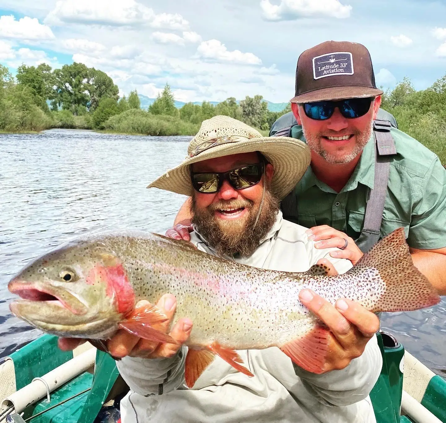 Two men holding a fish while sitting on a boat.