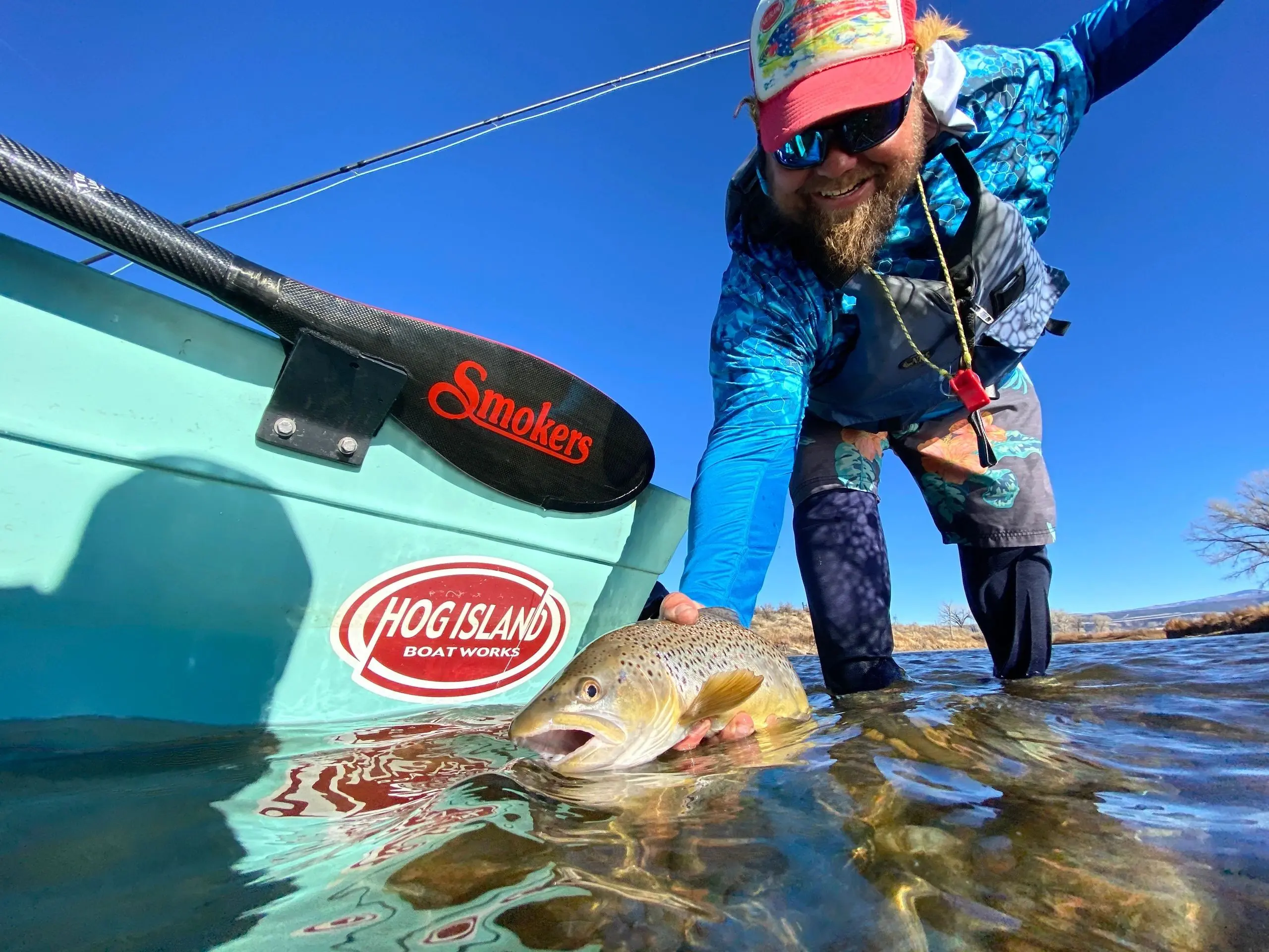 A man standing next to a boat with fish in it.