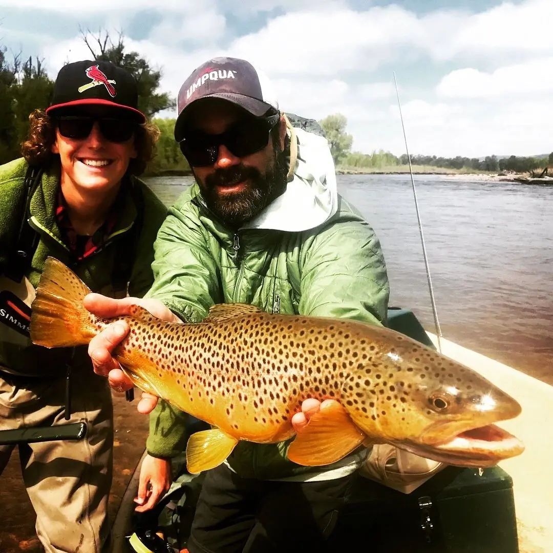 A man and woman holding a brown fish.