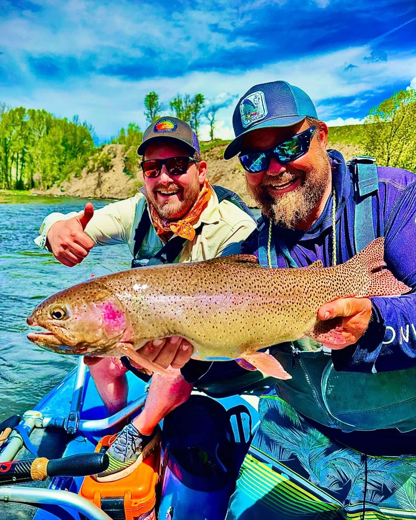 Two men holding a large fish while standing on the water.