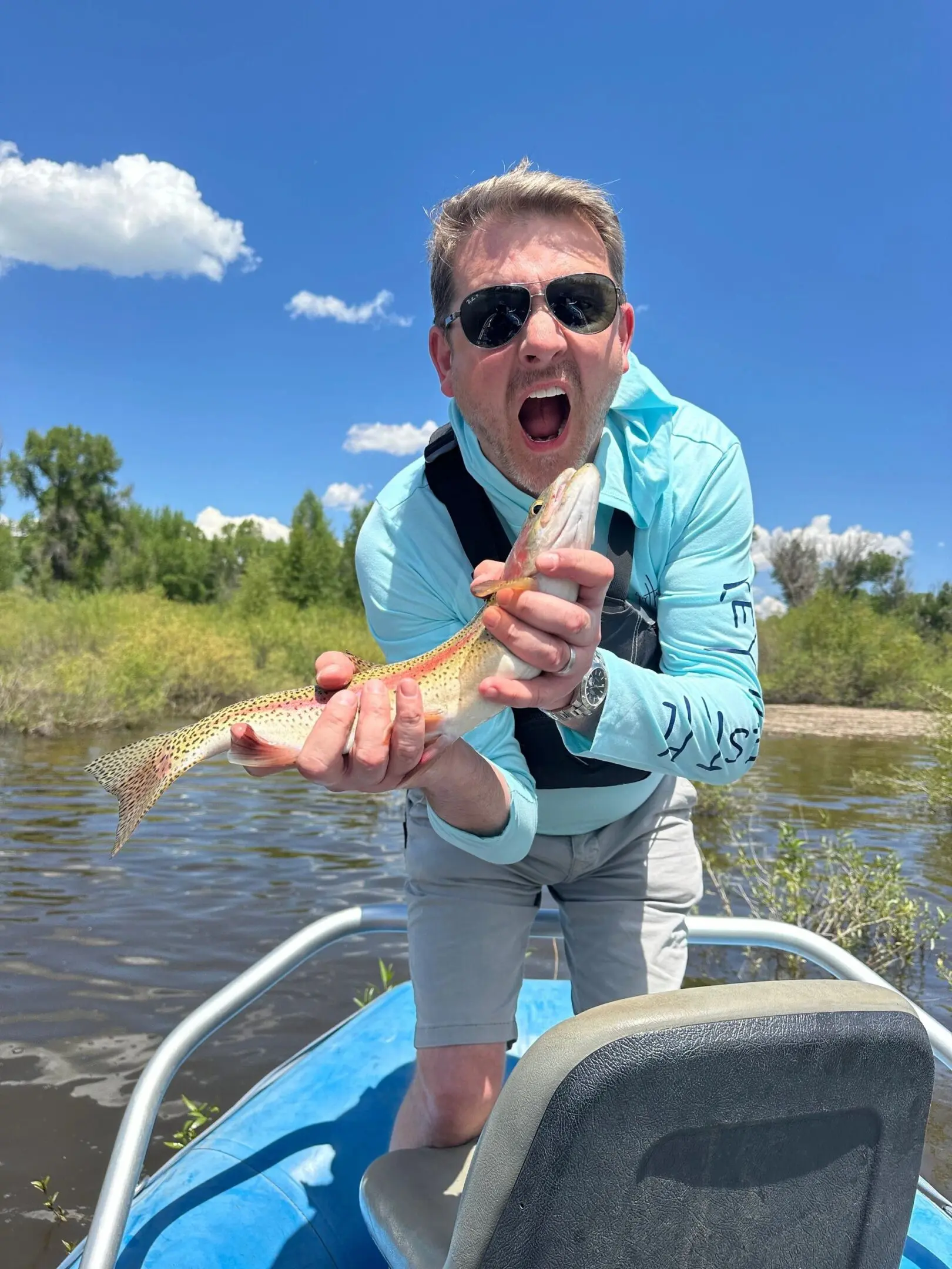 A man holding a fish in his mouth while sitting on a boat.