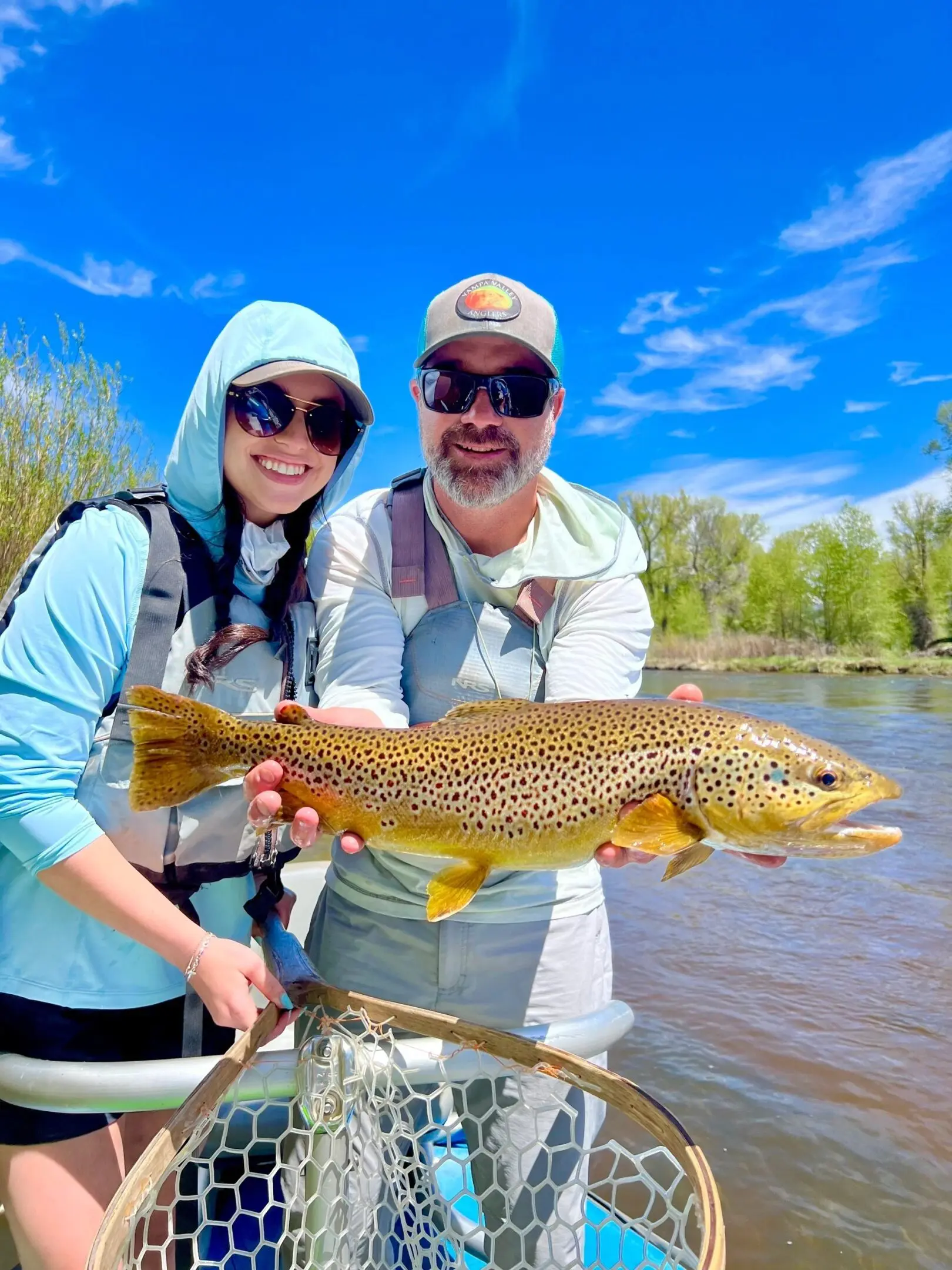 A man and woman holding a brown fish.