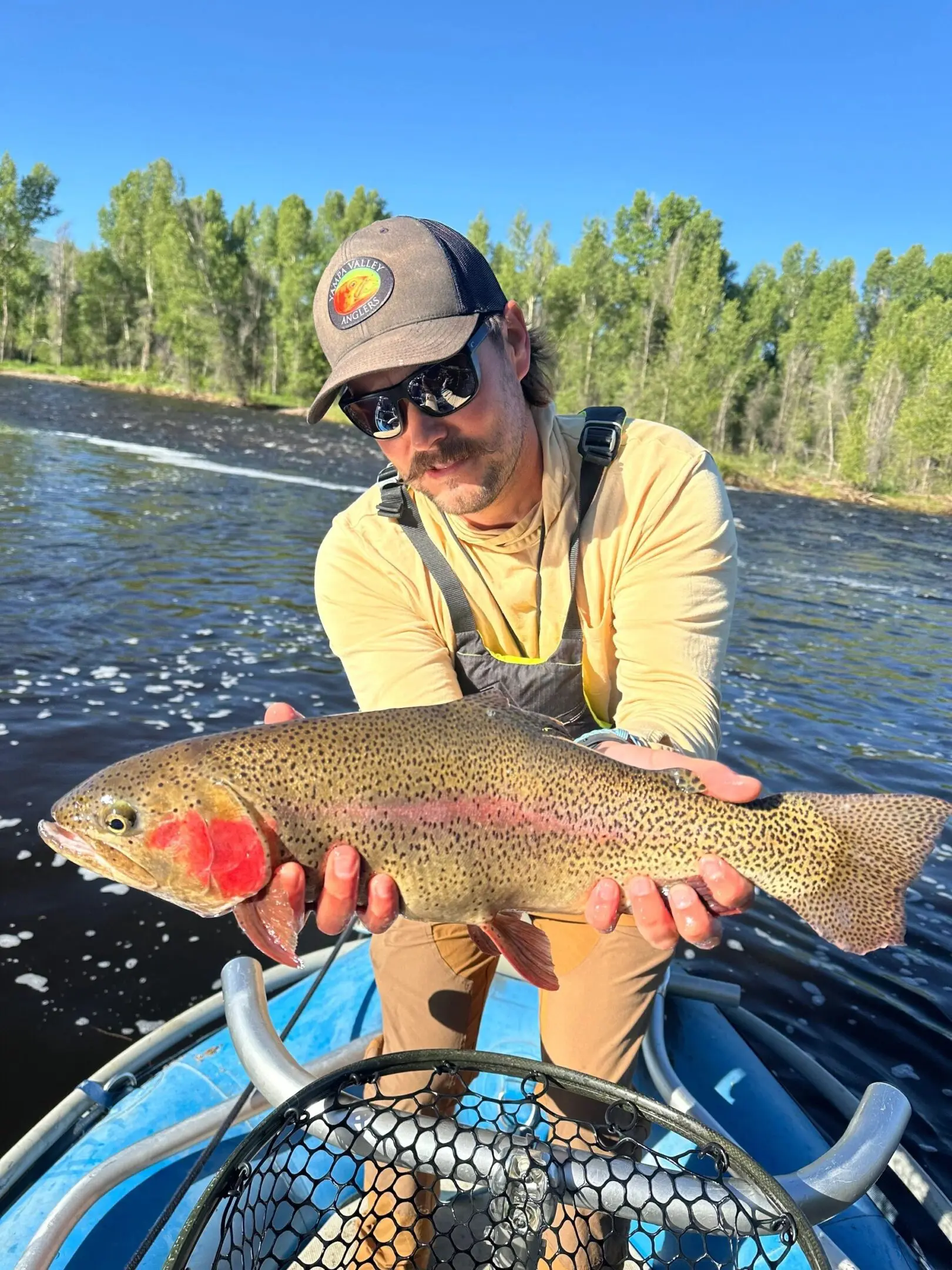 A man holding a fish while standing on top of a boat.