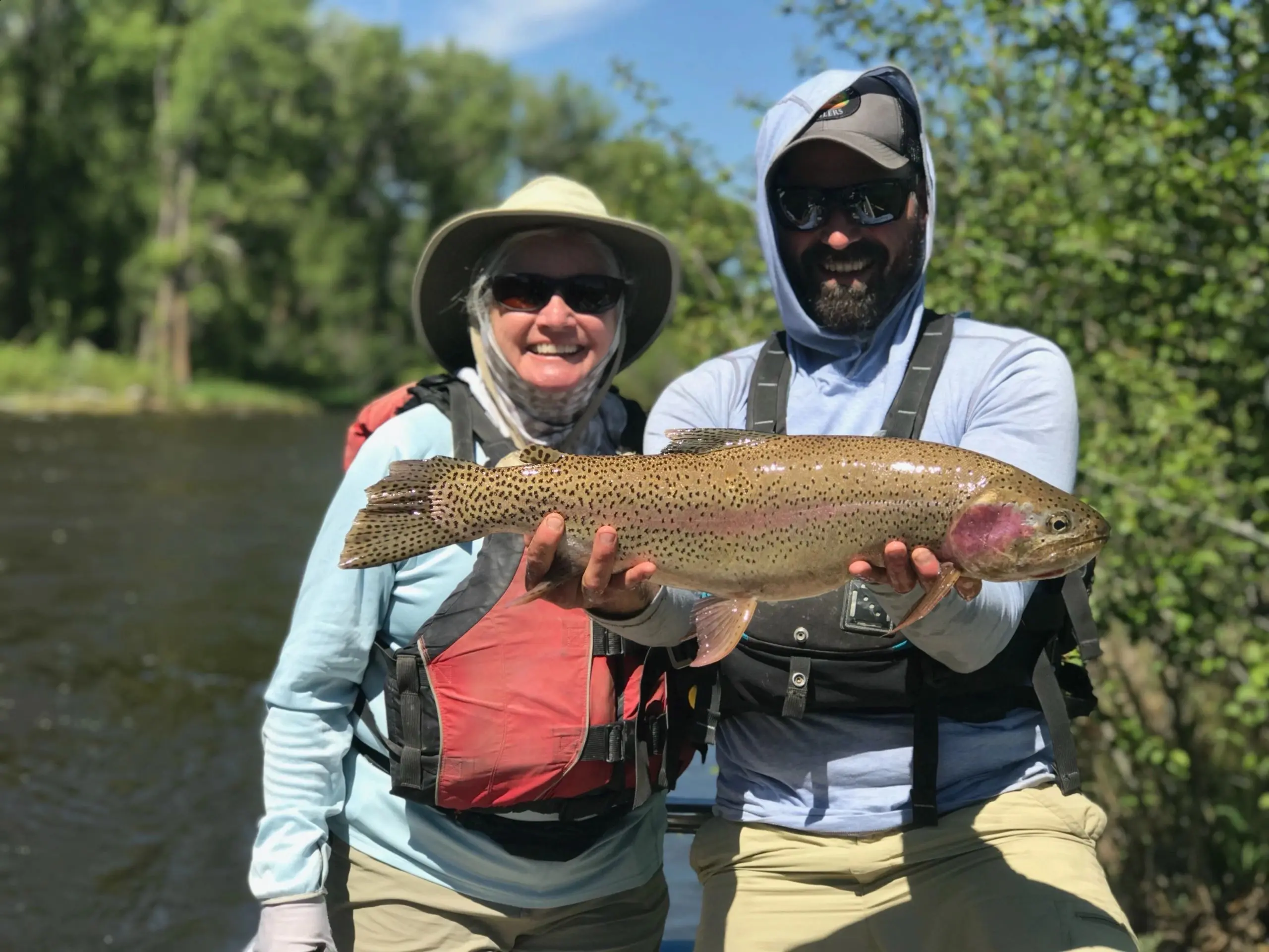 A man and woman holding a fish while standing in the water.