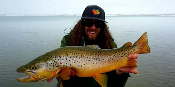 A man holding a brown fish in front of him.