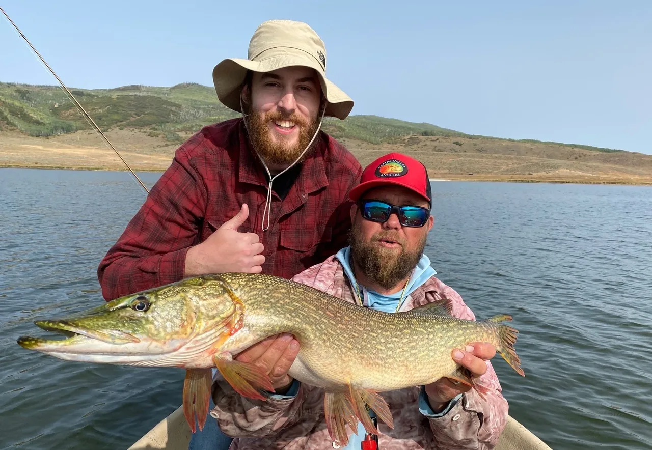 Two men holding a fish in the water.