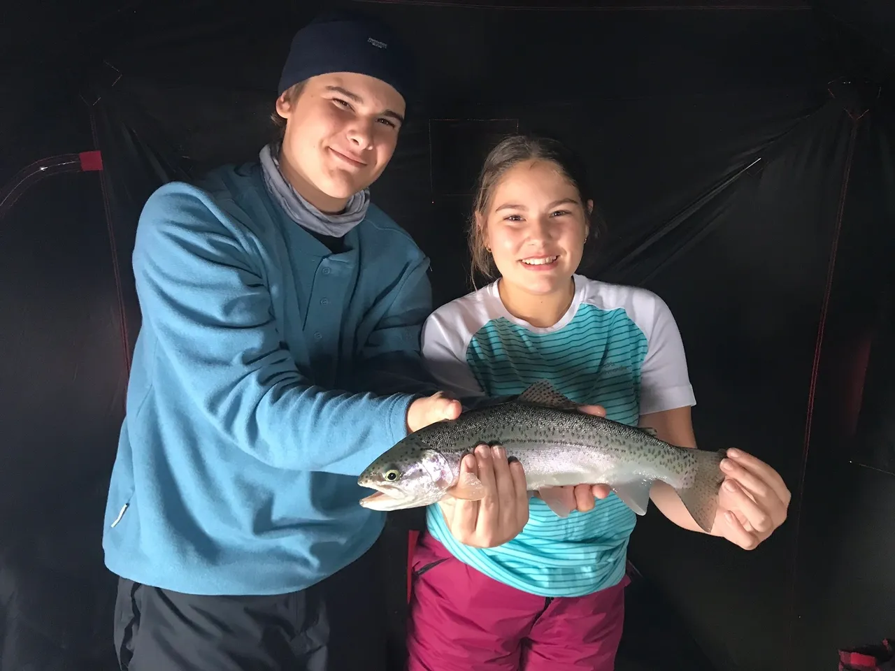 A man and woman holding a fish in their hands.