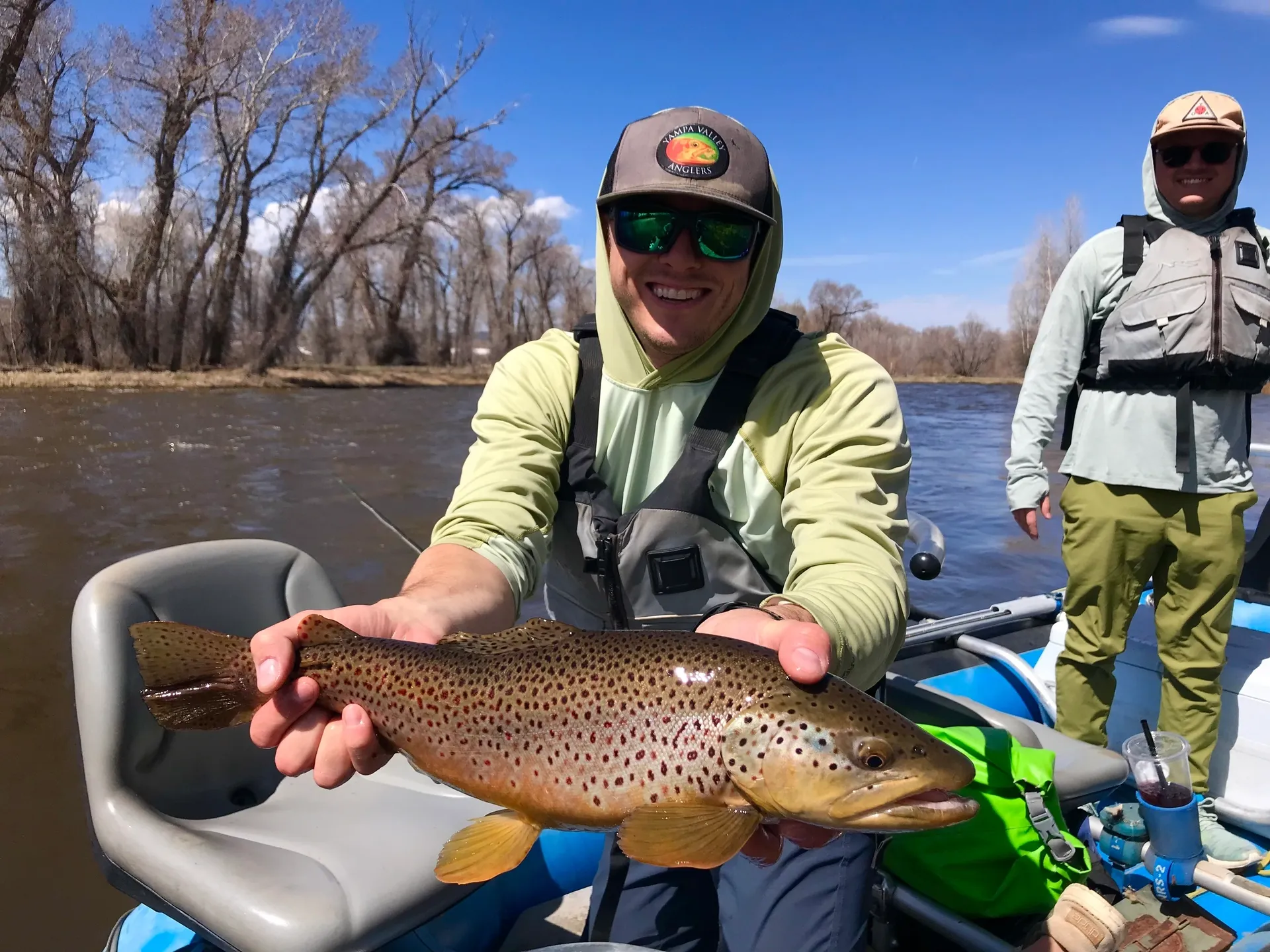 A man holding a brown fish while standing on top of a boat.