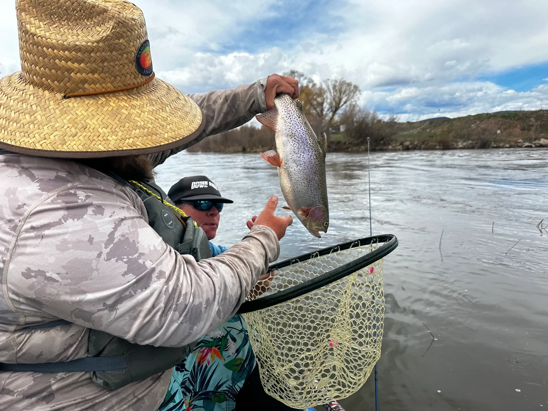 A man holding a fish while standing on a boat.