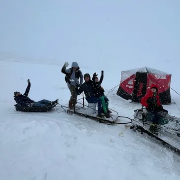 A group of people riding snow boards on top of a slope.