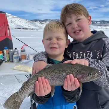 Two boys holding a fish in their hands.