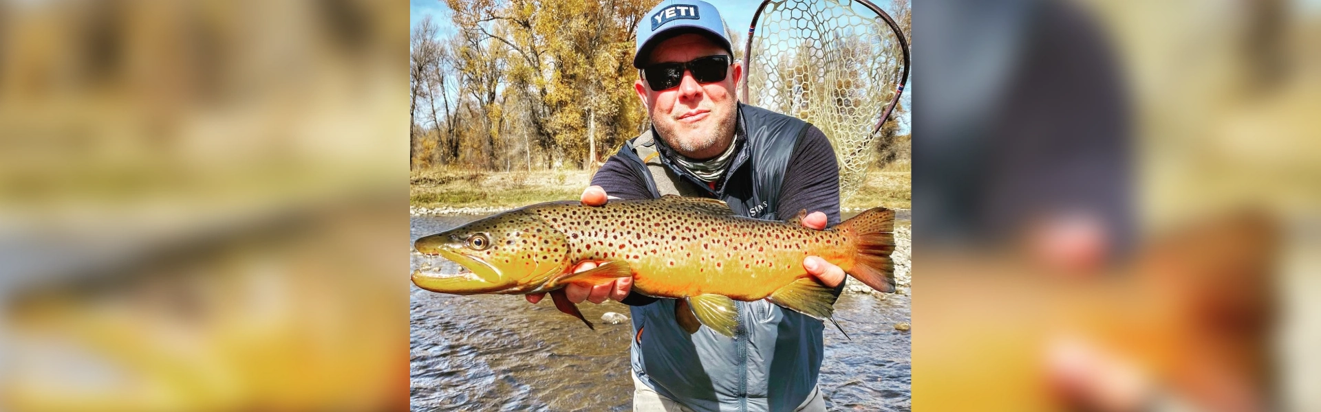 A man holding a brown fish in his hands.