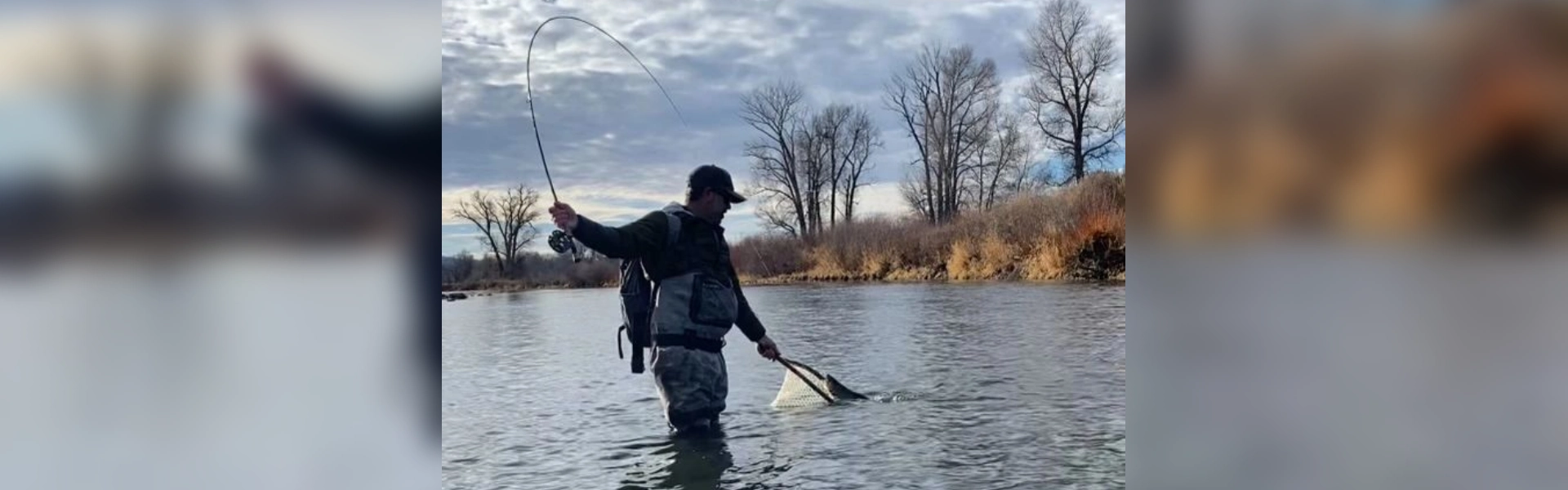 A man standing in the water holding a fishing rod.