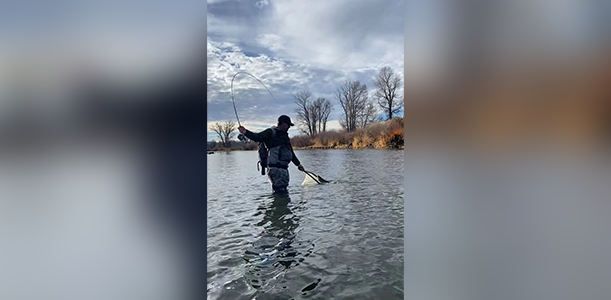 A man standing in the water holding a fishing rod.