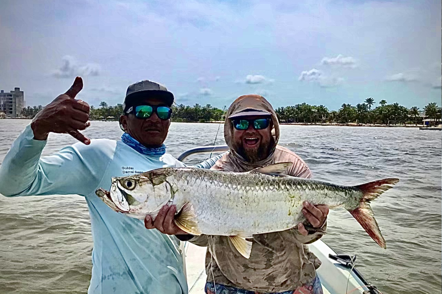 Two people holding a fish on the water.