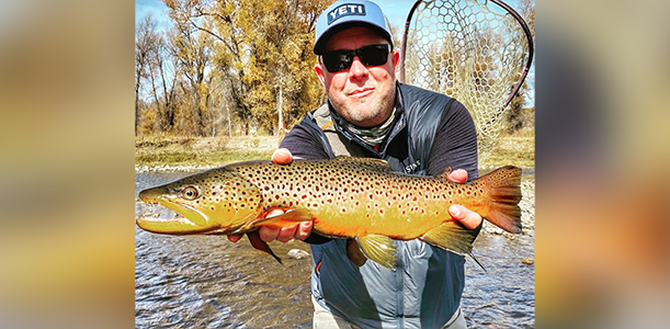 A man holding a brown fish in his hands.