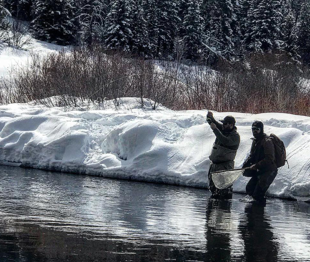 Two people in the water with a fishing rod.