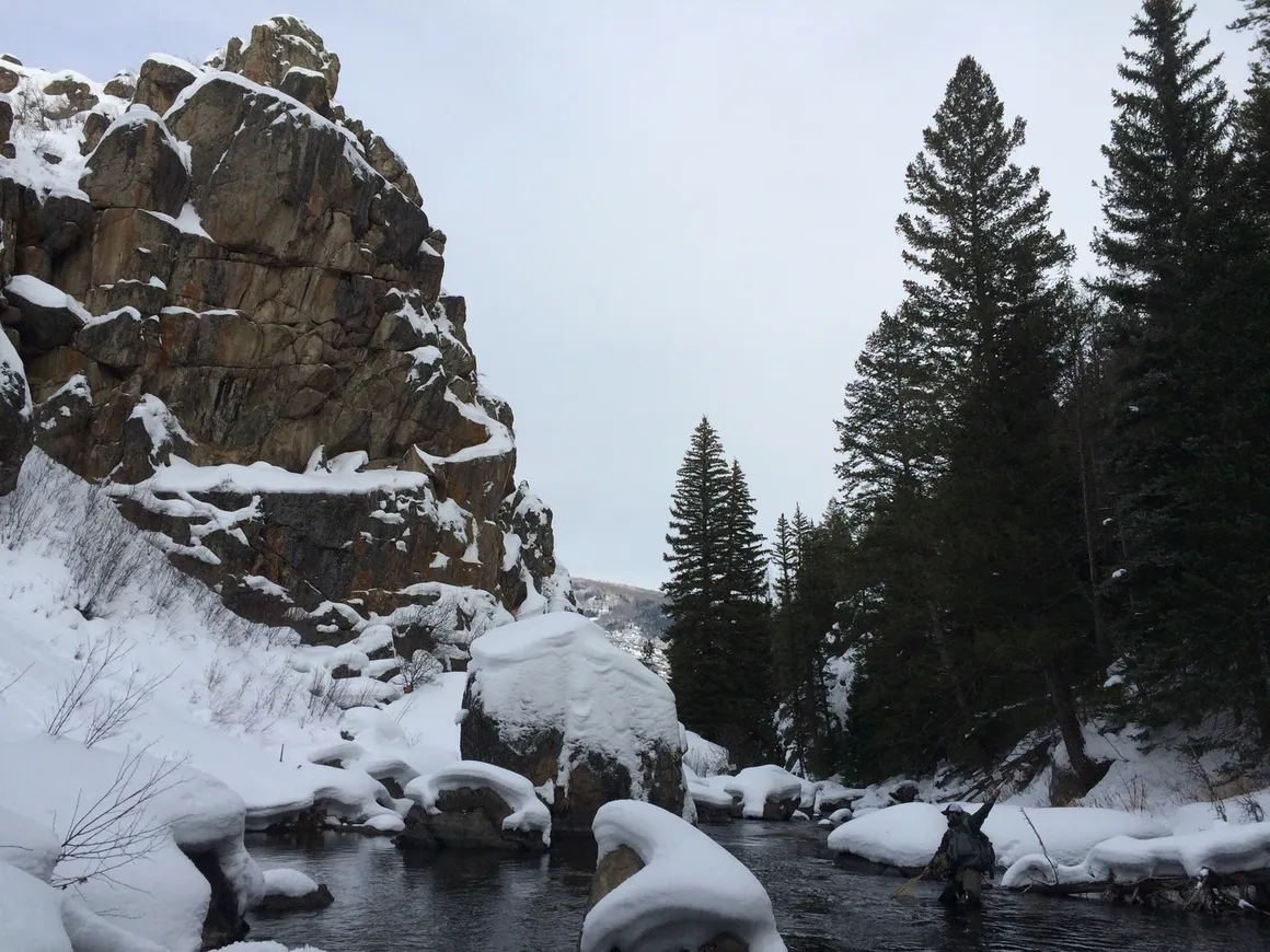 A person standing in the water near some rocks.