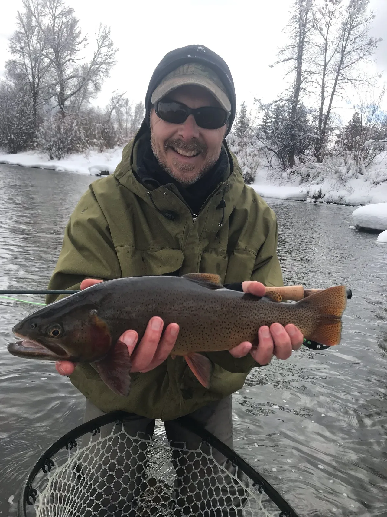 A man holding a fish while standing in the water.