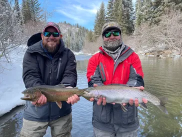 Two men holding a fish in the water.