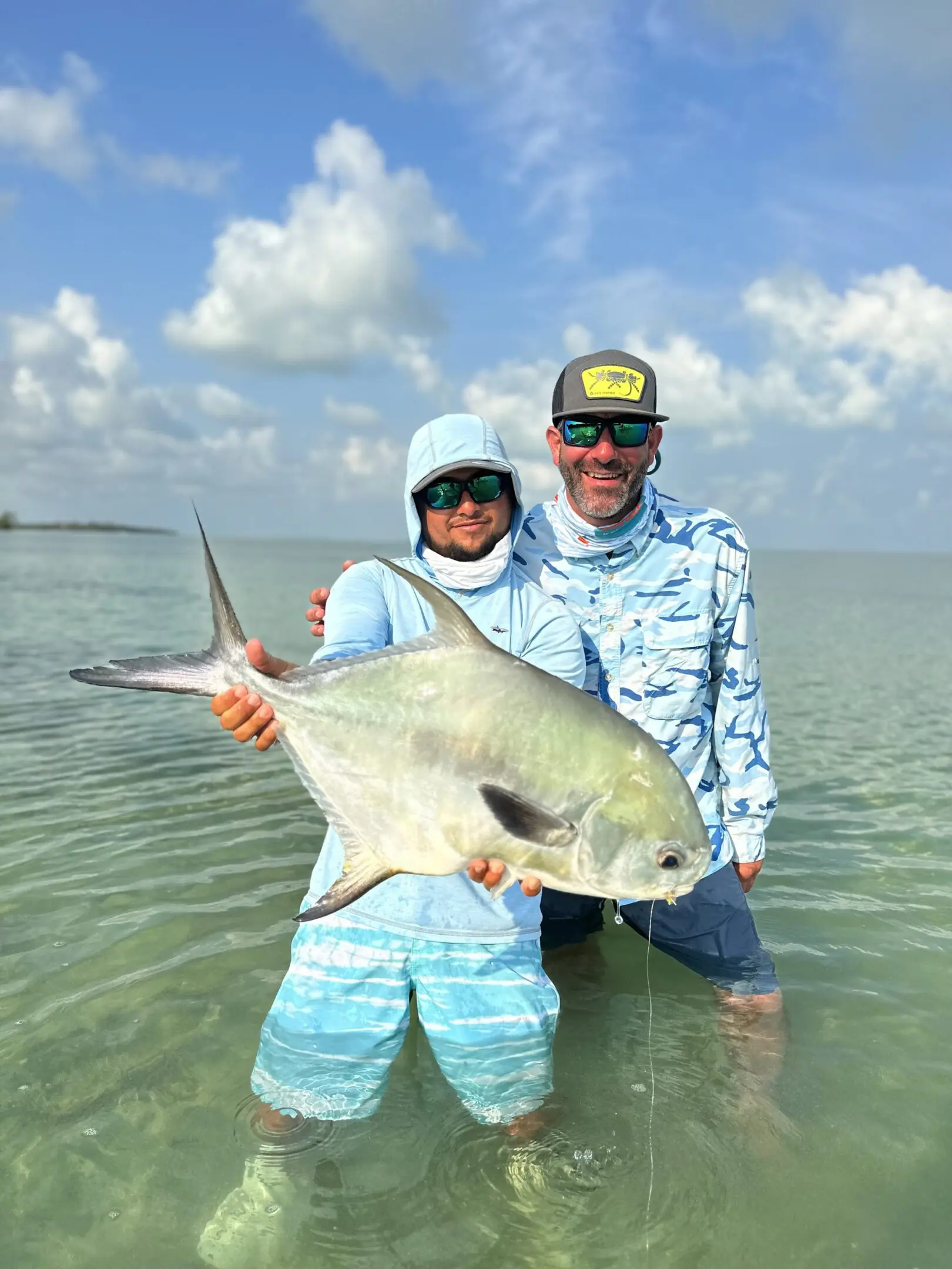 A man and woman holding a fish in the water.