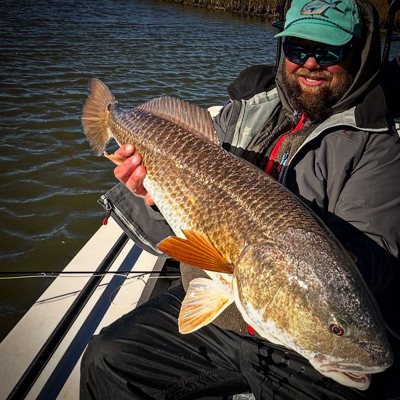 A man holding a large fish on top of a boat.