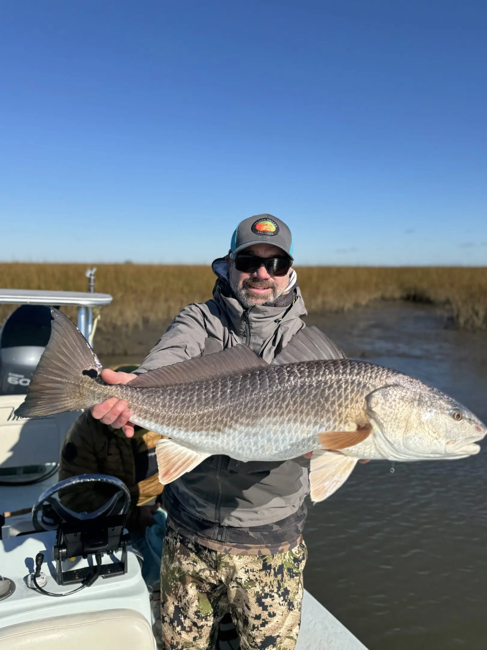 A man holding a fish while standing on top of a boat.